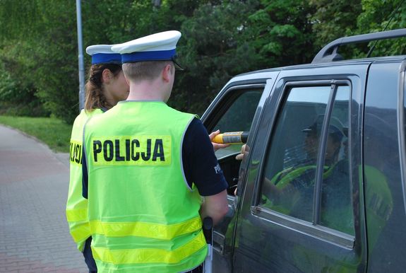 Na zdjęciu dwoje policjantów ruchu drogowego, którzy badają stan trzeźwości kierującego pojazdem.