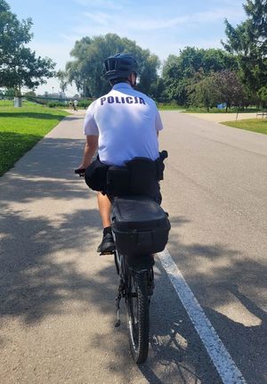 Na zdjęciu umundurowany policjant z patrolu rowerowego jadący na rowerze służbowym.