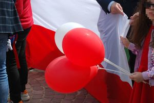 Na zdjęciu dziewczynka trzymająca białe i czerwone balony w tłumie ludzi.