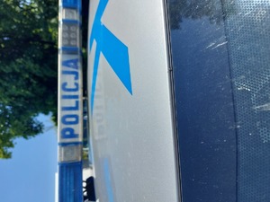 Na zdjęciu belka policyjnego radiowozu z napisem policja, w tle drzewa.