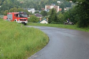 Na zdjęciu po prawej stronie pojazd typu quad obok niego umundurowany policjant. Po lewej stronie wóz strażacki, postronne osoby i policjant.