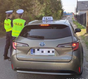 Na zdjeciu kontrolowany przez dwie umundurowane policjantki pojazd.