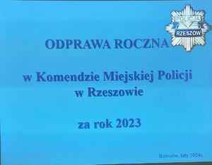 Na zdjeciu na niebieskim tle na pis o treści : Odprawa roczna w Komendzie Miejskiej Policji w Rzeszowie za rok 2023, w górnym prawym rogu policyjna gwiazda.