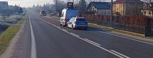 Na zdjęciu  na drodze stoi ambulans policyjny i straż pożarna, wzdłuż drogi domy.