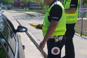 Na zdjęciu dwóch umundurowanych policjantów ruchu drogowego podczas kontroli drogowej.