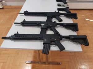 Na zdjęciu na stole leżą 3 repliki broni karabinka automatycznego M4 oraz  3 repliki broni Glock.