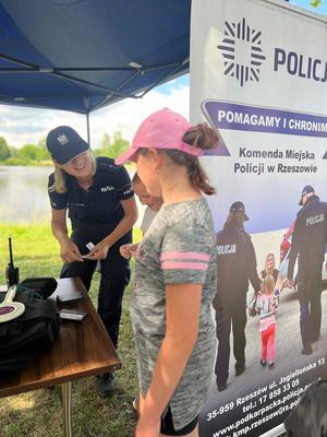 Na zdjęciu umundurowana policjantka przy stoisku profilaktycznym Komendy Miejskiej Policji w Rzeszowie.