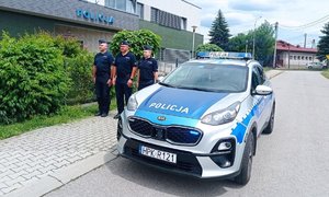 Na zdjęciu umundurowani policjanci przy oznakowanym radiowozie policyjnym.