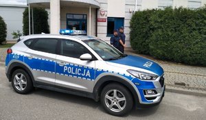 Na zdjęciu umundurowani policjanci przy oznakowanym radiowozie policyjnym.