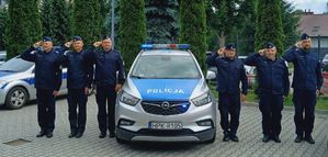 Na zdjęciu umundurowani policjanci przy oznakowanym radiowozie policyjnym.