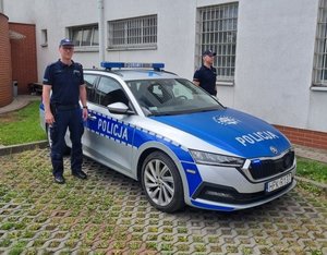 Na zdjęciu umundurowani policjanci przy oznakowanym radiowozie policyjnym.