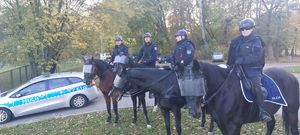 Na zdjęciu czworo policjantów na koniach służbowych, obok policyjny radiowóz.