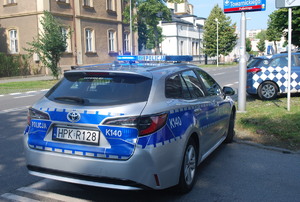 Na zdjęciu policyjny radiowóz. W tle budynki i drzewa.