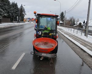 Na zdjeciu na ulicy stoi traktor z pługiem,przed nim policyjny van.