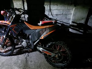 Na zdjęciu motocykl typu cross koloru pomarańczowego.