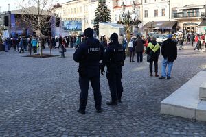 Na zdjeciu stoją tyłem umundurowani policjanci, patrzą w kierunku sceny.