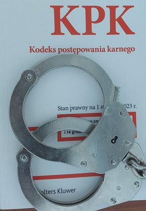 Na zdjęciu kodeks postępowania karnego, na nim leża policyjne kajdanki.