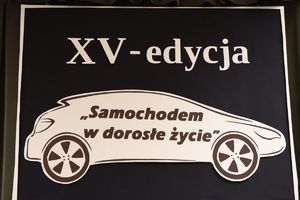 Na zdjęciu plakat a na nim graficzny obrys  auta i napis XV edycja samochodem w dorosłe życie.