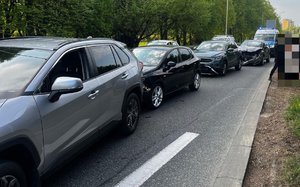 Na zdjęciu stojącen na pasie ruchu pojazdy, z tyłu policyjny radiowóz.