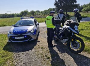 Na zdjęciu policjant ruchu drogowego, policyjny radiowóz oraz dwóch motocyklistów.