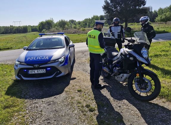 Na zdjęciu policjant ruchu drogowego, policyjny radiowóz oraz dwóch motocyklistów.