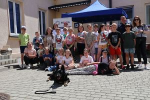 Na zdjeciu uczniowie SP nr 28 w Rzeszowie z wizytą w rzeszowskiej komendzie. Na środku przed dziećmi  leży na ziemi policyjny pies.