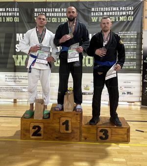 Na zdjęciu z lewej strony mł. asp. Damian Grendys. Obok niego na podium zawodnicy.