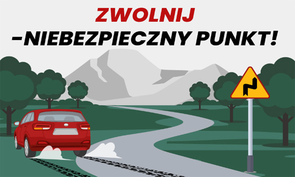 Na zdjęciu napis zwolnij niebezpieczny punku, poniżej kręta droga po której jedzie czerwone auto.