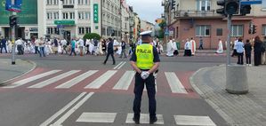 Na zdjęciu  umundurowany policjant, w tle procesja.