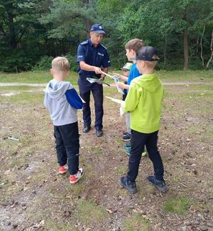 Na zdjeciu umundurowany policjant i trzech chłopców.