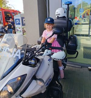 Na zdjeciu na policyjnym motocyklu siedzi chłopiec, na głowie na policyjna czapka.