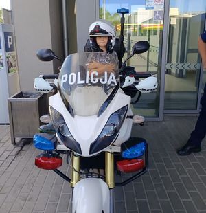Na zdjeciu na policyjnym motocyklu siedzi chłopiec, na głowie na policyjny kask.