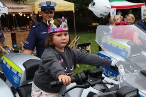 Na zdjęciu na policyjnym motocyklu siedzi dziewczynka z korona na głowie.