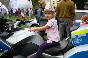 Na zdjęciu na policyjnym motocyklu siedzi dziewczynka z korona na głowie.
