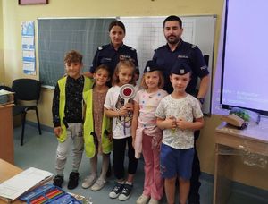 Na zdjęciu dwoje umundurowanych policjantów w szkolnej sali z uczniami.