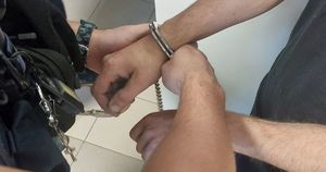 Na zdjęciu policjant zapina kajdanki na męskie ręce.