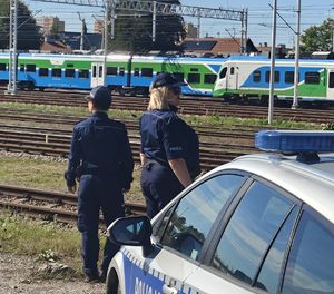 Na zdjęciu dwie umundurowane policjantki patrzą w stronę torów kolejowych.