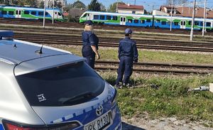 Na zdjęciu dwie umundurowane policjantki patrzą w stronę torów kolejowych.