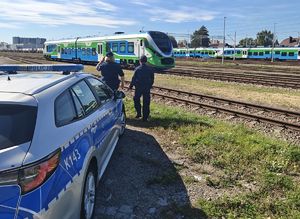 Na zdjęciu dwie umundurowane policjantki patrzą w stronę torów kolejowych.