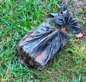 Na zdjęciu, na trawie leży prostokątny przedmiot owinięty w czarny worek.