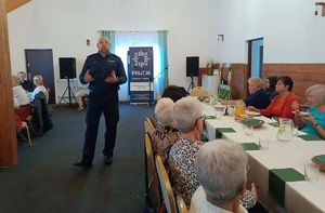 Na zdjęciu umundurowany policjant na spotkaniu z seniorami.
