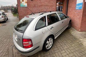 Na zdjeciu pojazd koloru srebrnego przy ścianie narożnej budynku.