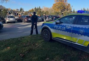 Na zdjęciu umundurowany policjant obok radiowozu.