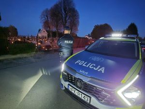 Na zdjęciu radiowóz, przed nim policjant.