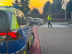 Na zdjęciu policyjny radiowóz, w tle policjant.