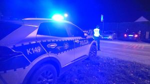 Na zdjęciu radiowóz przed nim policjant.