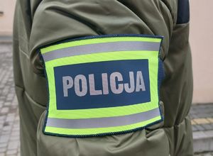 Na zdjęciu naramienna opaska odblaskowa z napisem policja.