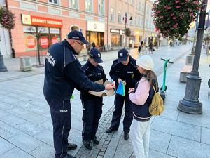 Na zdjęciu policjanci rozdają przechodniom odblaski.