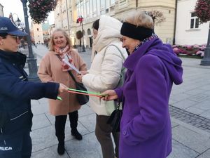 Na zdjęciu policjanci rozdają przechodniom odblaski.