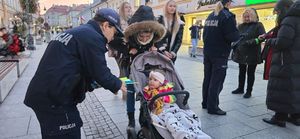 Na zdjęciu policjanci rozdają przechodniom odblaski.